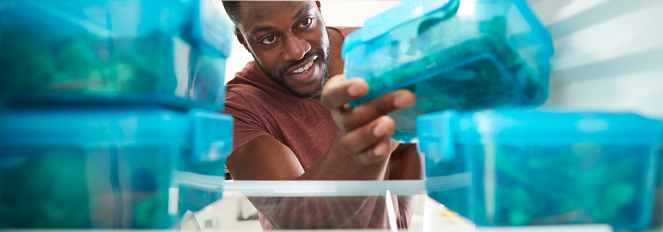 Man reaching into fridge for healthy meal in blue conta