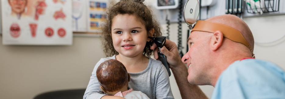 Dr. Matthew Brown, ENT, checks the ear of a young child